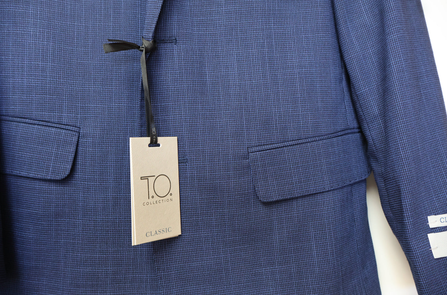 Close-up of T.O. boys suit fabric showing blue on black nailshead texture and front pocket detail