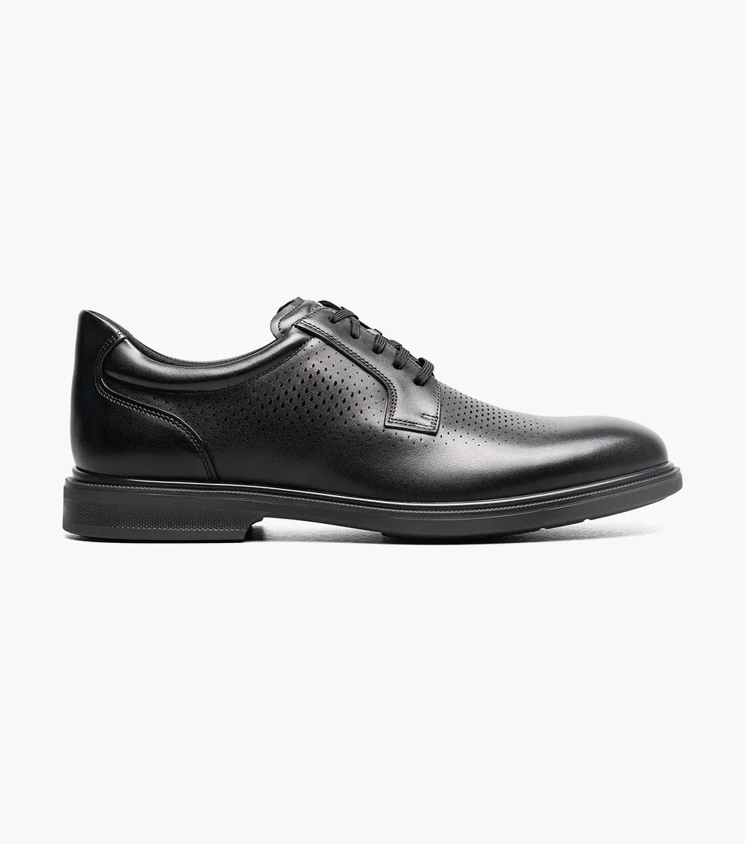 Side view of a black leather men’s lace-up dress shoe with perforated detailing and a low rubber sole.