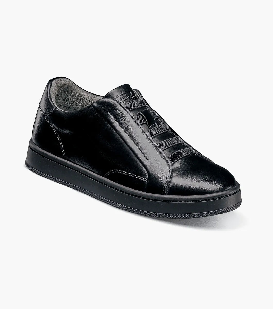 A black leather low-top sneaker with a glossy finish, featuring decorative stitched details on the sides and tongue, set against a plain light gray background.