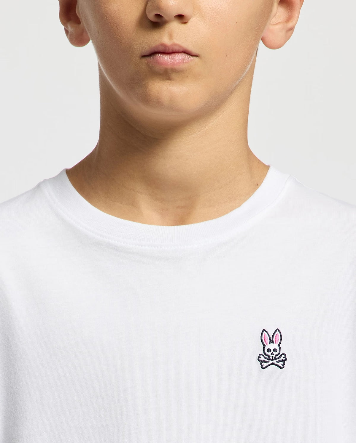 Close-up of Psycho Bunny Kids white T-shirt neckline and embroidered logo