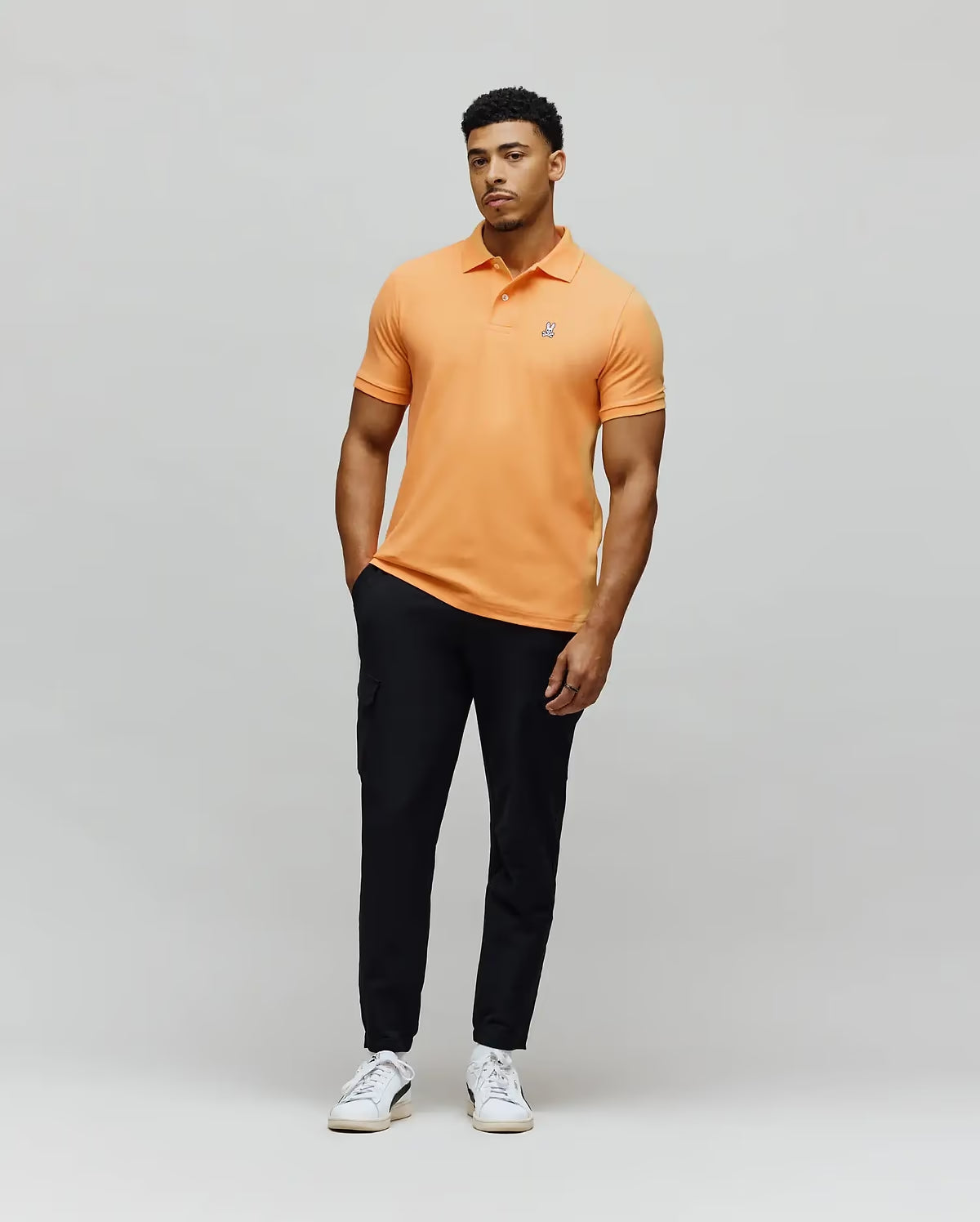 Model Wearing Psycho Bunny Men's Classic Pique Polo in Papaya Orange